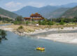 Tourists raft through the river near a Bhutanese temple