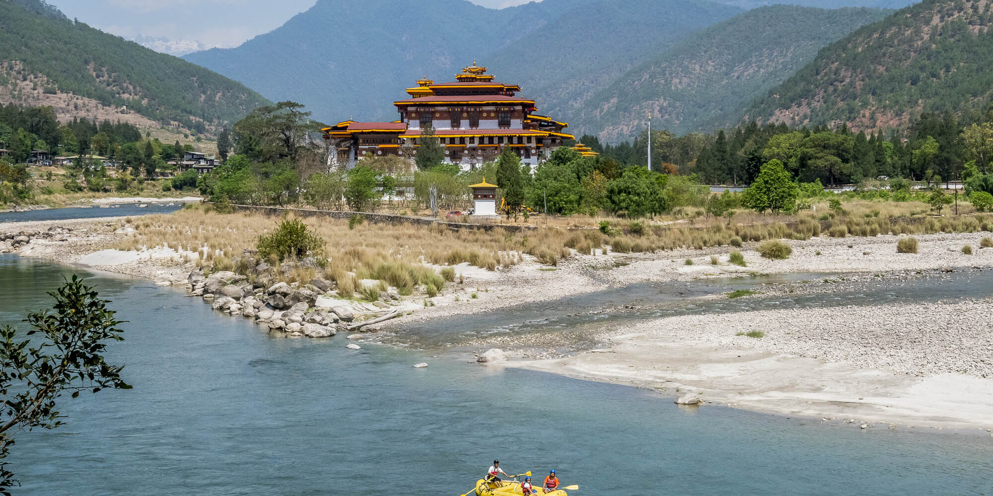 Tourists raft through the river near a Bhutanese temple