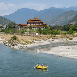 Tourists raft through the river near a Bhutanese temple