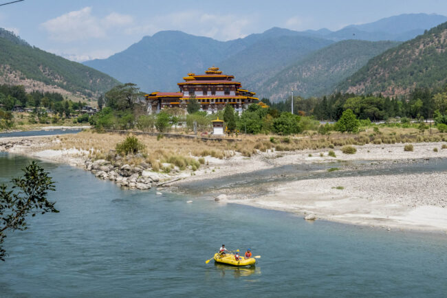 Tourists raft through the river near a Bhutanese temple