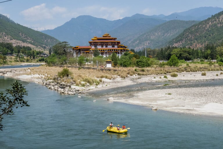 Tourists raft through the river near a Bhutanese temple