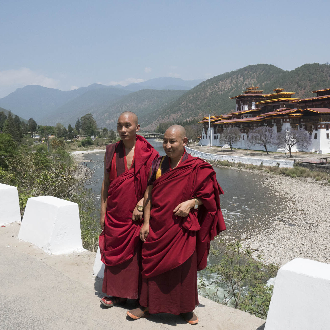 Two Bhutanese monks pose for photos in front of a temple